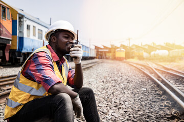 Portrait of Africa American man engineering holding railing and with wear hardhat in front of train...