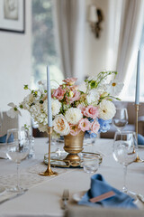Blue wedding decor. Festive table decorated with flowers on the center, candles, silverware and...