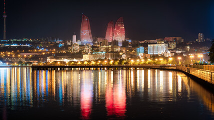 Fototapeta na wymiar Baku, Azerbaijan - July 2019: Night view of Baku with the Flame Towers skyscrapers, television tower and the seaside of the Caspian sea