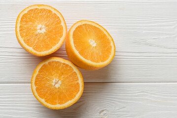 Three halves of an orange on a white wood background.