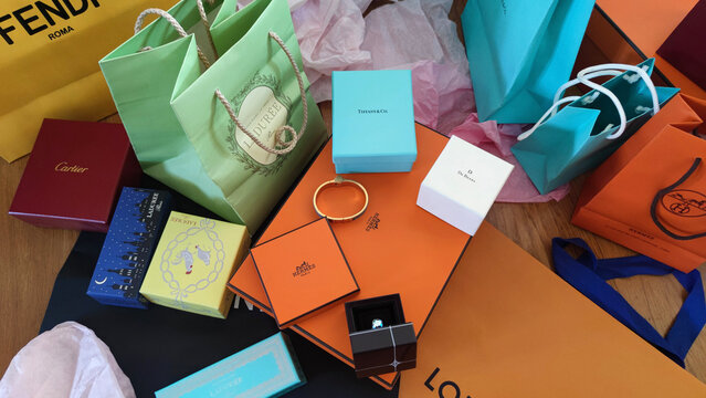 Several colorful shopping bags from famous French or luxury brands and a wedding ring