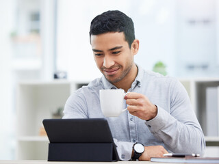 I guess I have interesting day ahead of me. Shot of a young businessman drinking coffee while using his digital tablet.