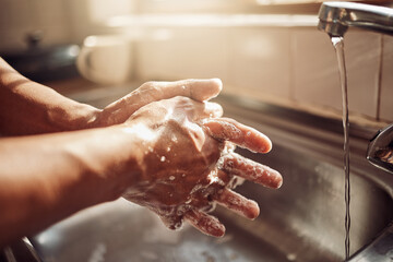 No germs, no problem. Shot of an unrecognisable man washing his hands in the kitchen sink at home.