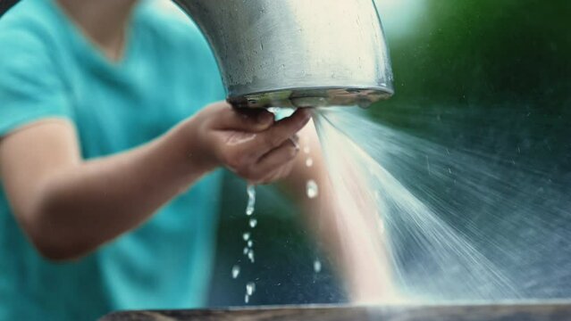 Child plays public water faucet making water pressure