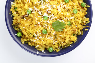 Kande Pohay OR Aloo Pohe is a popular Indian breakfast recipe made using Flattened rice, usually served with hot tea. Served in a bowl over moody background. Selective focus