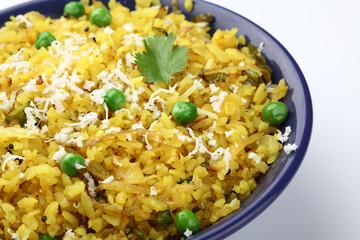 Kande Pohay OR Aloo Pohe is a popular Indian breakfast recipe made using Flattened rice, usually served with hot tea. Served in a bowl over moody background. Selective focus