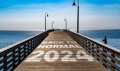 Back to Normal 2024 written on the wooden planks of a pier on the Pacific Coast	
