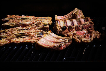 juicy beef rib and pork rib slowly being made on the grill on the fire at a gas barbecue