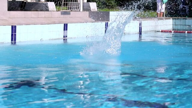 Sports competitions. The guy jumps from a springboard and dives into the pool. Performs several revolutions in the air. The springboard is in the open air