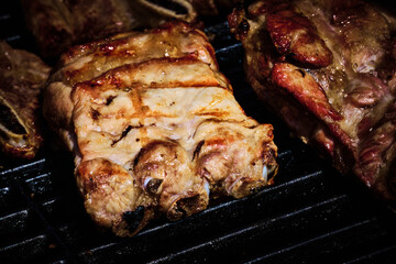 juicy beef rib and pork rib slowly being made on the grill on the fire at a gas barbecue