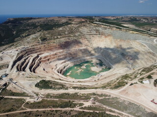 Aerial view industrial of opencast mining quarry with lots of machinery at work - extracting fluxes...