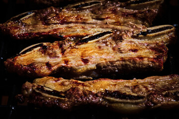 juicy beef rib and pork rib slowly being made on the grill on the fire at a gas barbecue