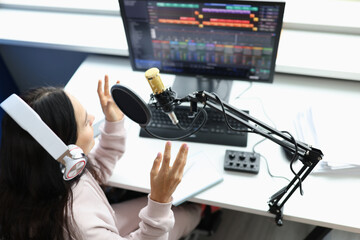 Woman in headphones in front of microphone broadcasts radio
