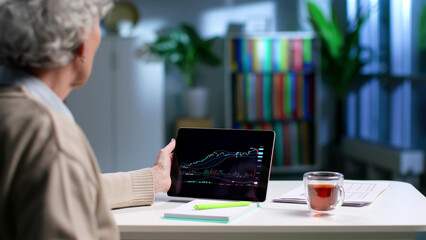 Senior woman use digital tablet with graph having online investment courses