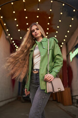 Fashion portrait of a confident girl in a green jacket. Clothing advertising concept.