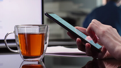 Cropped shot of businesswoman scrolling smartphone at workplace