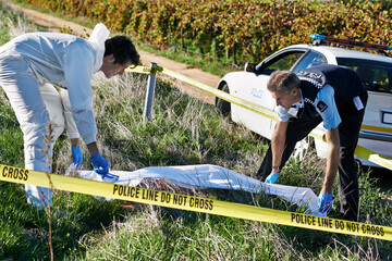 Covering the body. Shot of two investigators picking up a body bag at a crime scene.