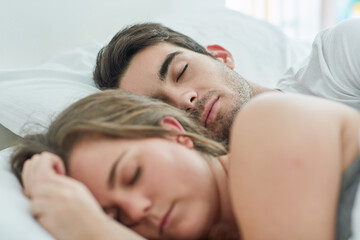 No need to rush today. Shot of a relaxed young couple sleeping in bed together at home.