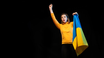 Beautiful Ukrainian girl with the national state flag of Ukraine on black background. Copy space. Russian Ukrainian War. Help and Pray for Ukraine. Stop war.