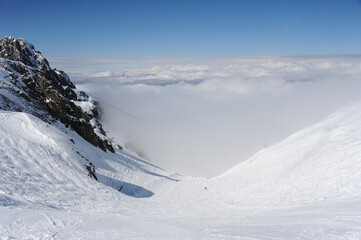 Ski resort valley under clouds by winter in French alps