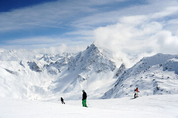 Fototapeta na wymiar Winter scenery with people skiing at the peak of French alps