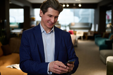 Handsome successful businessman, interior designer typing text on his smartphone