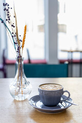 Morning cup of coffee on the background of the window in the backlight of natural sunlight. Cappuccino coffee in a beautiful cup.