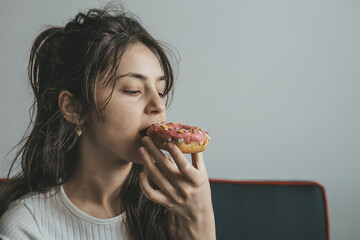 .Close up portrait of pleased pretty girl eating donuts