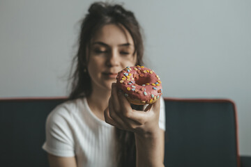 .Close up portrait of pleased pretty girl eating donuts