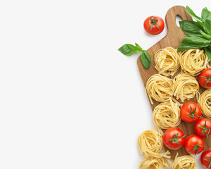 culinary background. Wooden kitchen board with raw pasta, tomatoes and basil on a light gray background