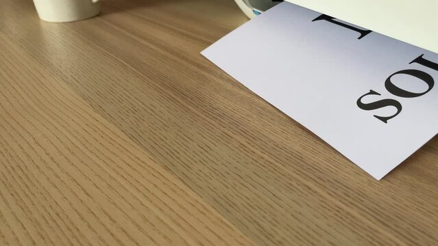Printing &ldquo;NO SOLICITING&rdquo; text written message word on paper sheet document. Close up A4 page being printed from multifunction scanner printer on wooden desk in office. Hand take paper from printer