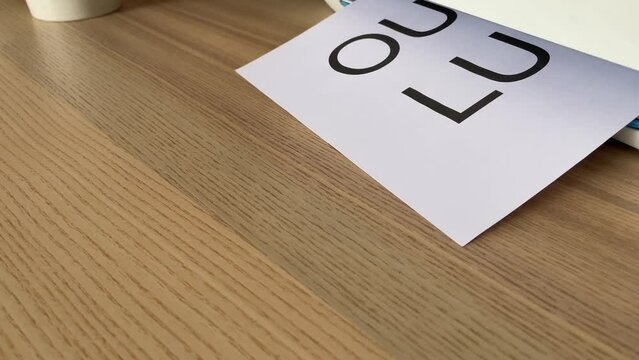 Printing &ldquo;OUT TO LUNCH&rdquo; text written message word on paper sheet document. Close up A4 page being printed from multifunction scanner printer on wooden desk in office. Hand take paper from printer