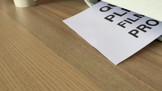Printing &ldquo;QUIET PLEASE FILMING IN PROGRESS&rdquo; text written message word on paper sheet document. A4 page being printed from multifunction scanner printer on wooden desk in office. Hand take paper