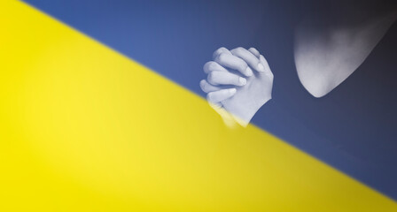 Flag Ukraine with woman praying and worshiping hands in worship to GOD on flag background, folded...