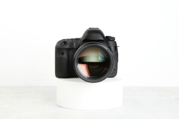 Big Black DSLR Digital Camera full frame sensor with lens on gray white cement background.