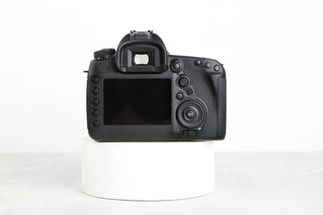 Big Black DSLR Digital Camera full frame sensor with lens on gray white cement background.
