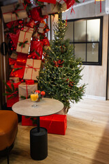 Shiny glass of hot orange grog cocktail served on counter in cafe on new year decoration background