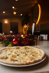 Four cheese pizza quattro formaggi with glass of wine on background with new year decorations.