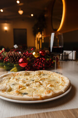 Four cheese pizza quattro formaggi with glass of wine on background with new year decorations.