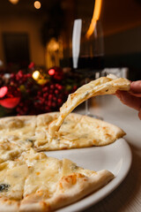 Four cheese pizza quattro formaggi with glass of wine on background with new year decorations.