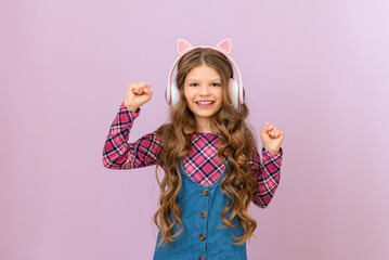 A cheerful little girl in new headphones listens to music.