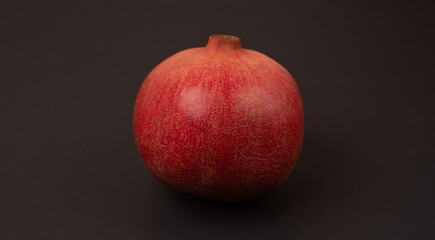 Ripe red pomegranate close up on a dark background. 