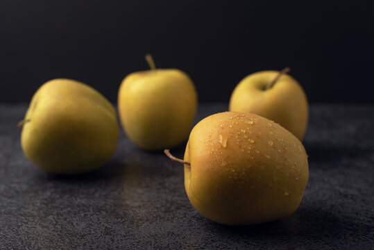 Ripe golden apples with water drops on it on a dark background. 