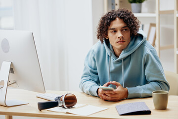 portrait of a man in a blue jacket in front of a computer with phone technologies