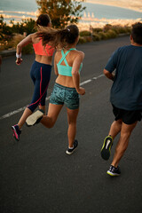 Meet up and get your sweat on. Shot of a fitness group running along a rural highway.
