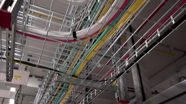 The server room has a lot of wires. Many rows of wires on the ceiling of the facility, technical ans internet concept. Action. Bottom view of bonded wires, many power cables in datacenter.