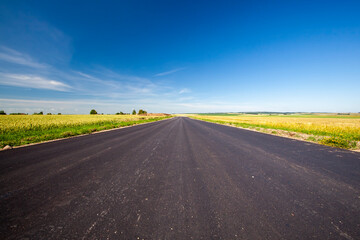 an asphalt road with a blue cloudless sky