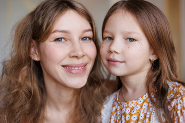 Portrait of lovely family mother and daughter embracing and kissing each other at home. Happy sweet woman with little 6-year-old girl in yellow dresses, family look, sitting on floor. Sweet family