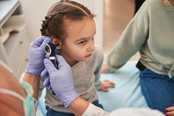 Male ENT examines ear of small patient with special device