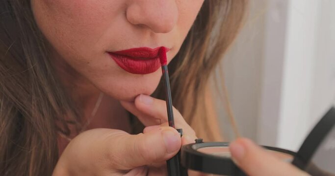Close up slow-motion footage of how a girl with a burgundy pencil for makeup outlines the contour of the lips, preparation for the performance